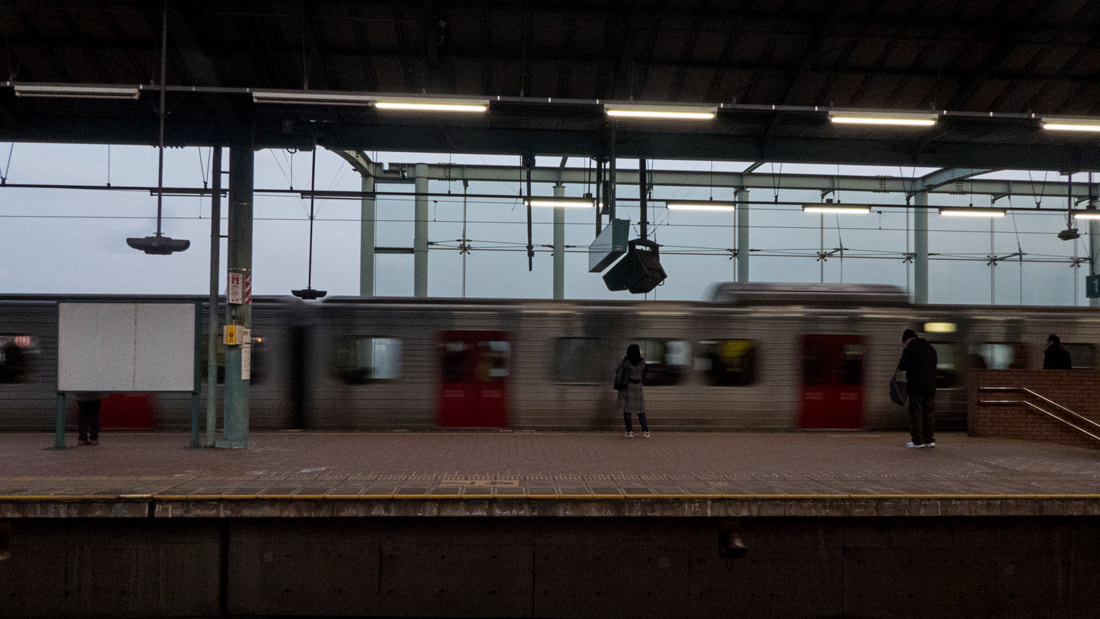 Blurred train passing before the clear silhouette of a young woman.