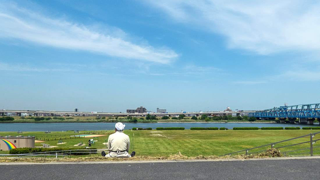Old worker taking a break while looking at the Arakawa River, Tokyo, 